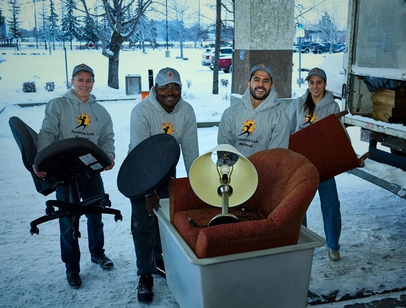 Sunshine Junk Removal crew loading a couch, office chair and lamp into the truck in winter